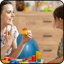 A smiling teacher playing with building blocks with a child